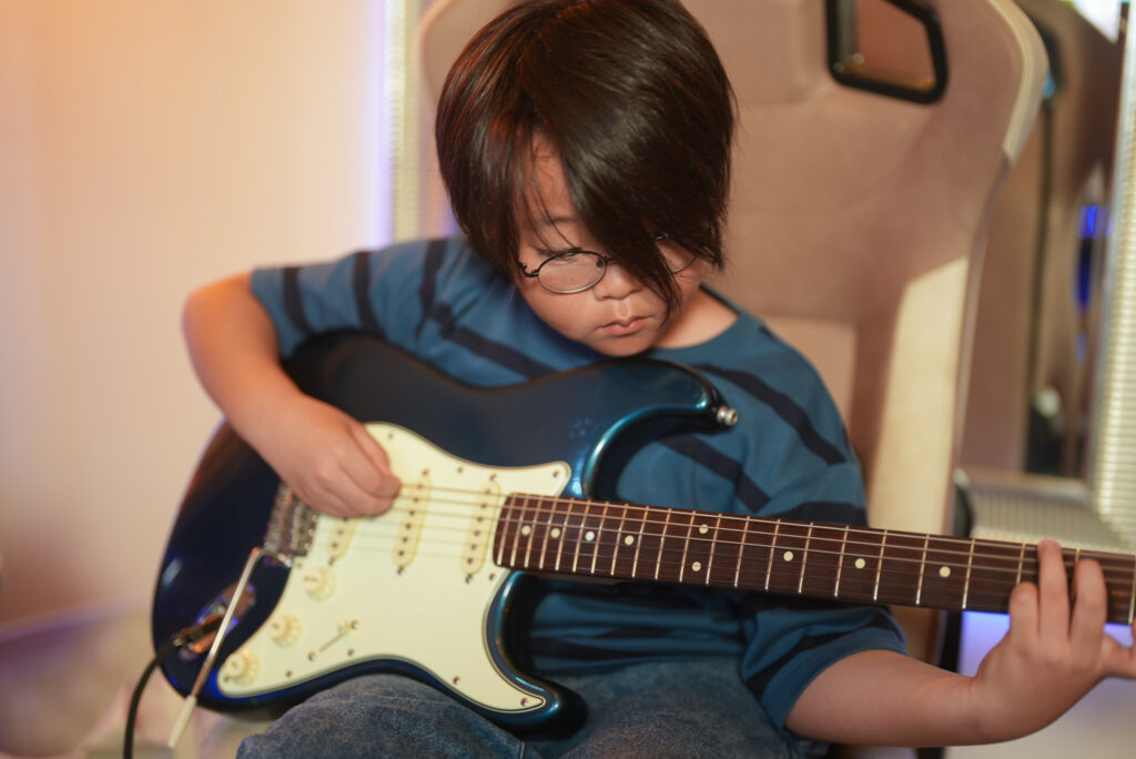 レッスンでギターを弾く小学4年生の生徒