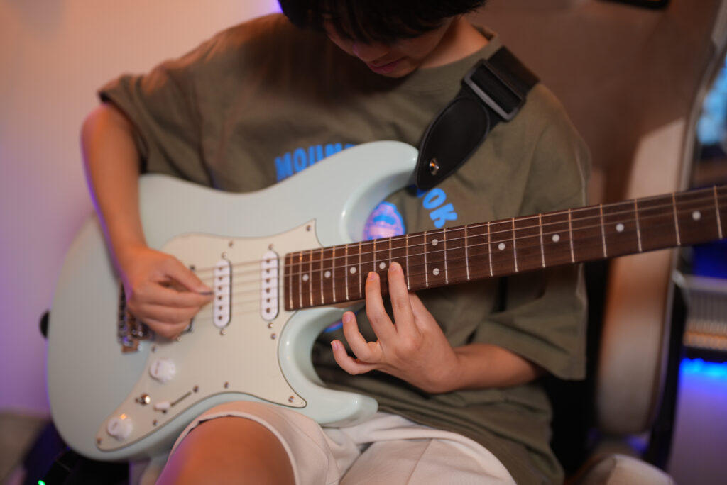 レッスンでギターを弾く中学生の女性生徒