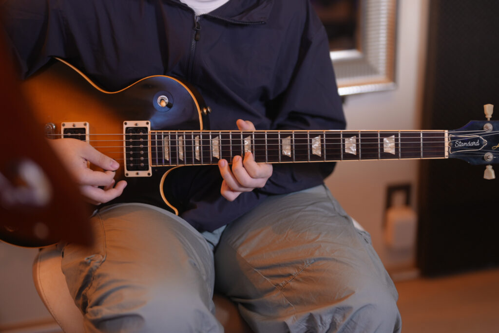 レッスンでギターを弾く男性生徒