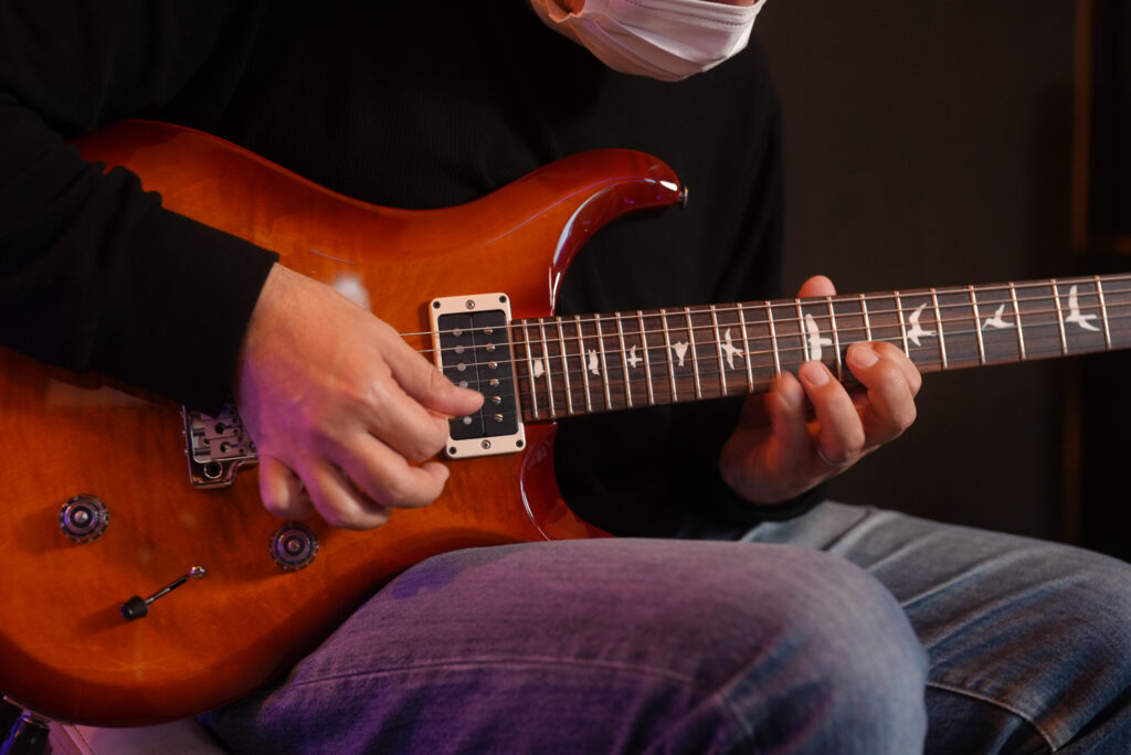 レッスンでギターを弾く男性生徒