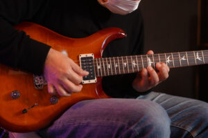 レッスンでギターを弾く男性生徒