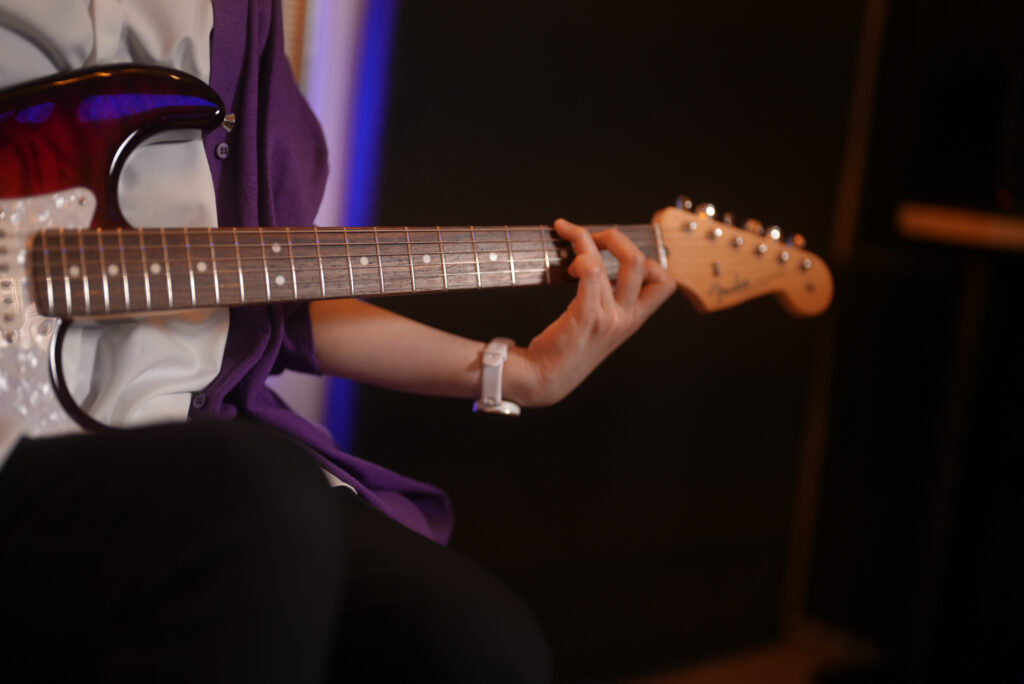 レッスンでギターを弾く女性生徒