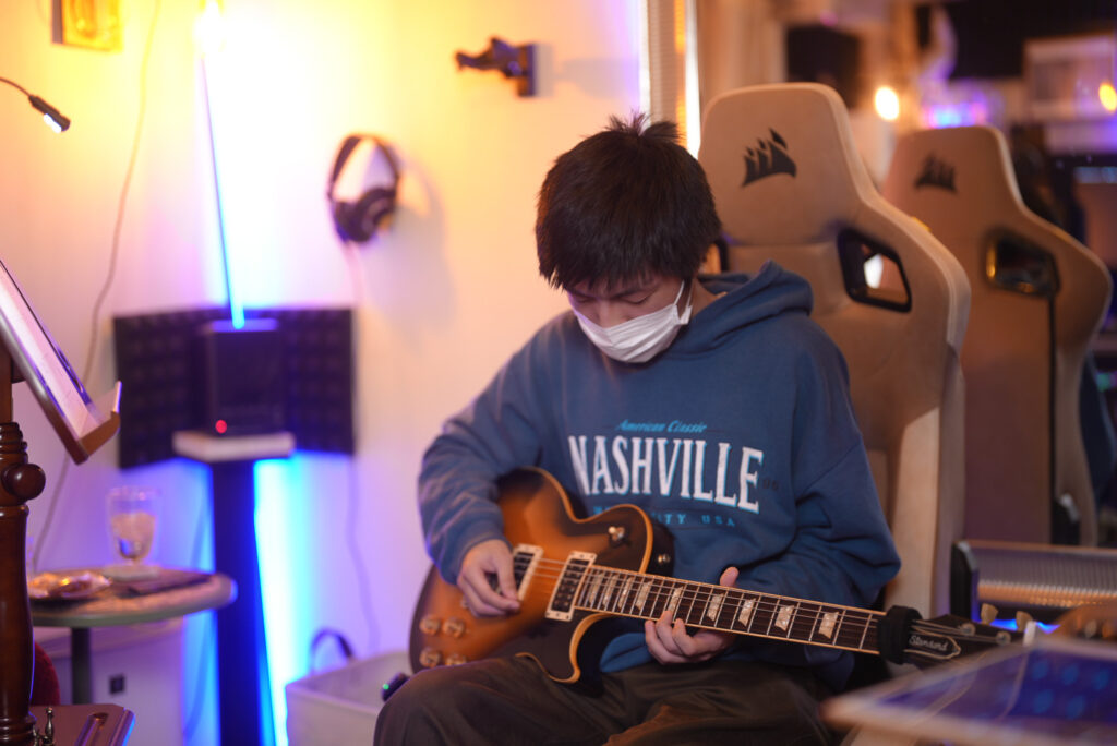 レッスンでギターを弾く男性生徒