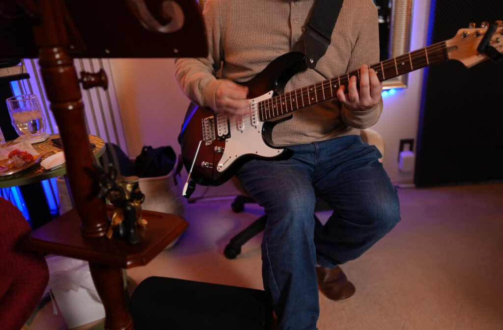 レッスンでギターを弾く男性生徒