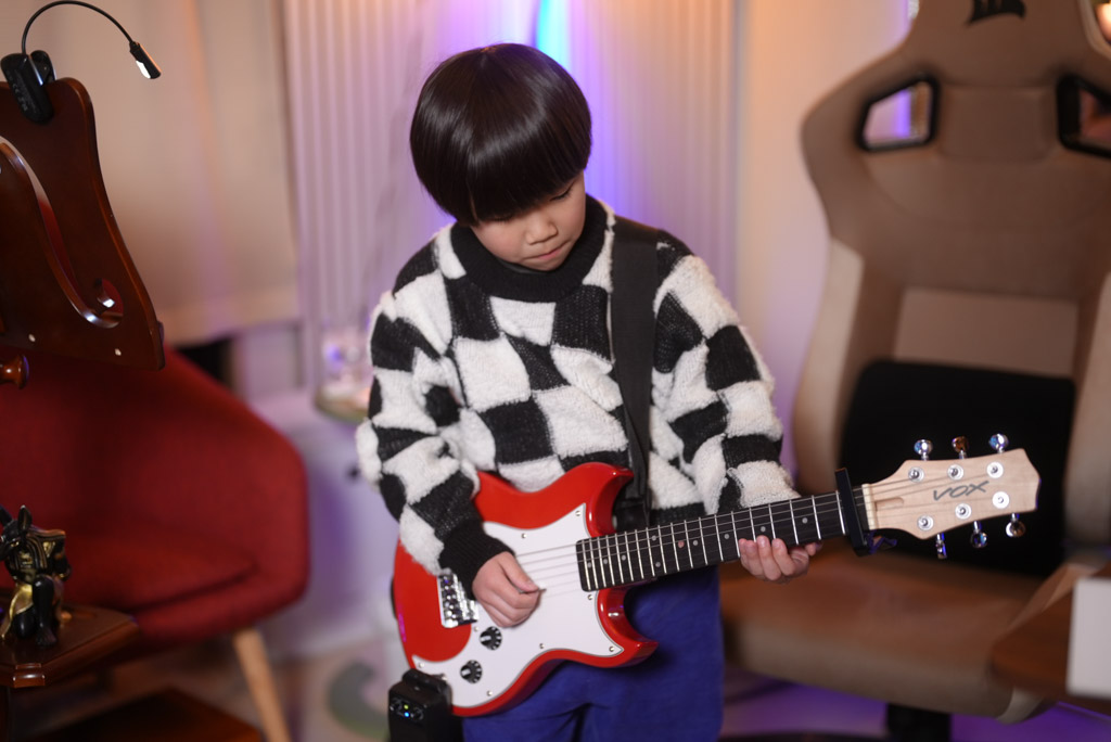 レッスンでギターを弾く小学1年生の生徒