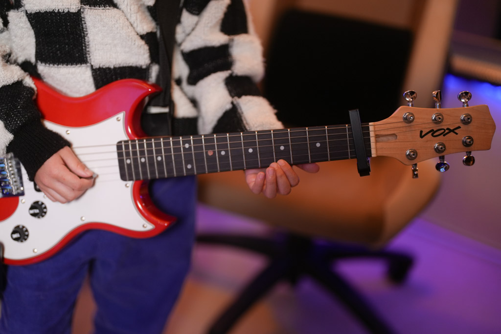 レッスンでギターを弾く小学1年生の生徒