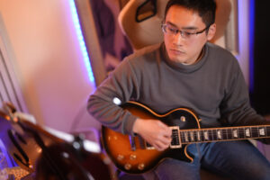 レッスンでギターを弾く男性生徒