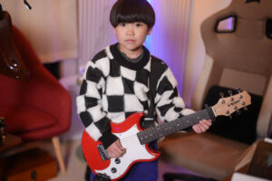 レッスンでギターを弾く小学1年生の生徒