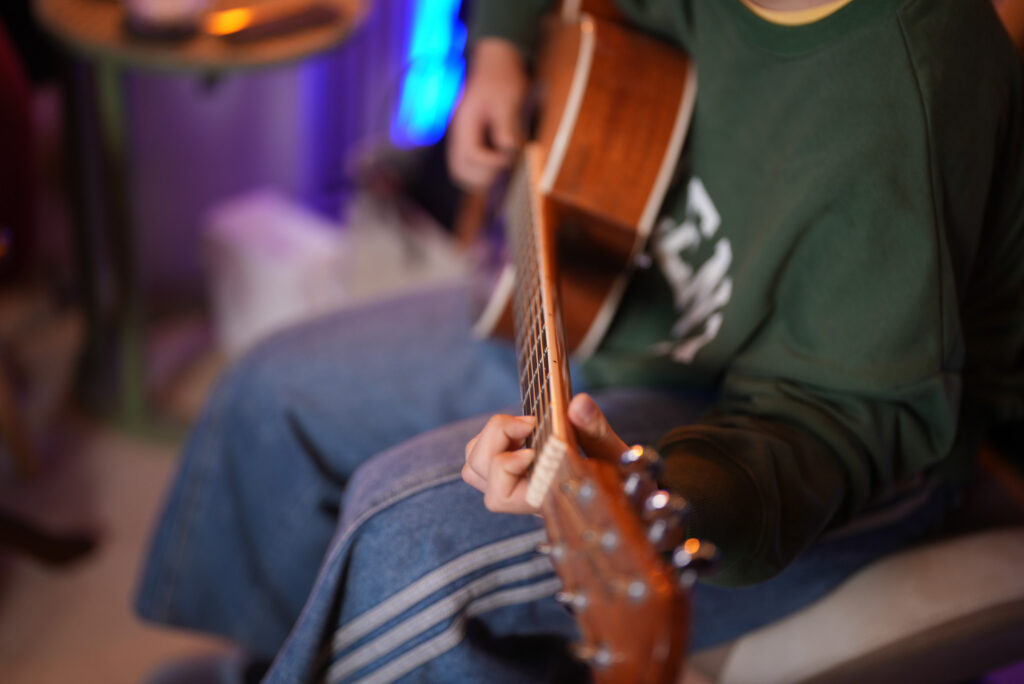 レッスンでギターを弾く中学生、女性生徒