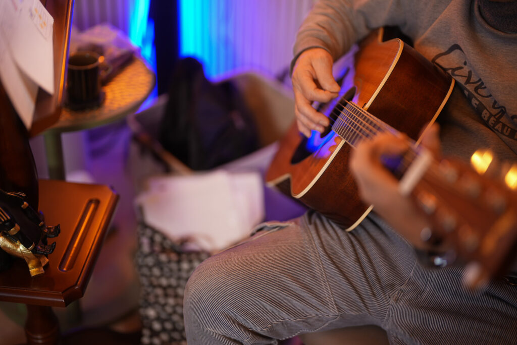 レッスンでギターを弾く男性生徒