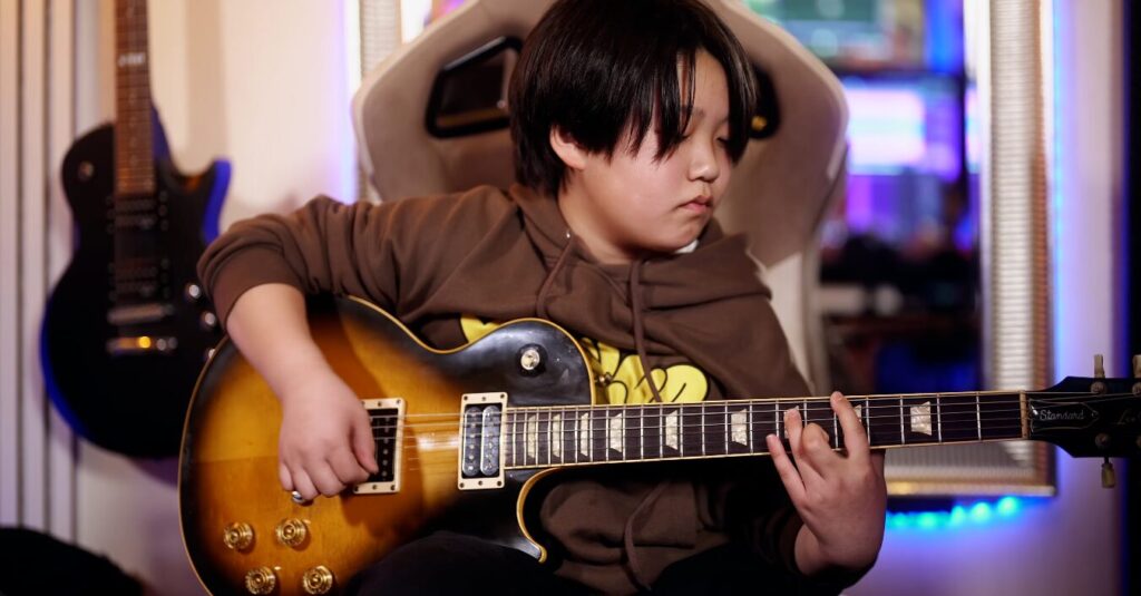 レッスンでギターを弾く男性、中学生の生徒