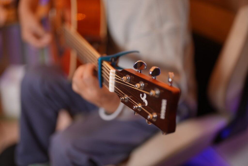 レッスンでギターを弾く男性生徒と講師