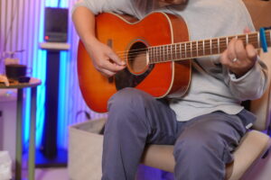 レッスンでギターを弾く男性生徒と講師