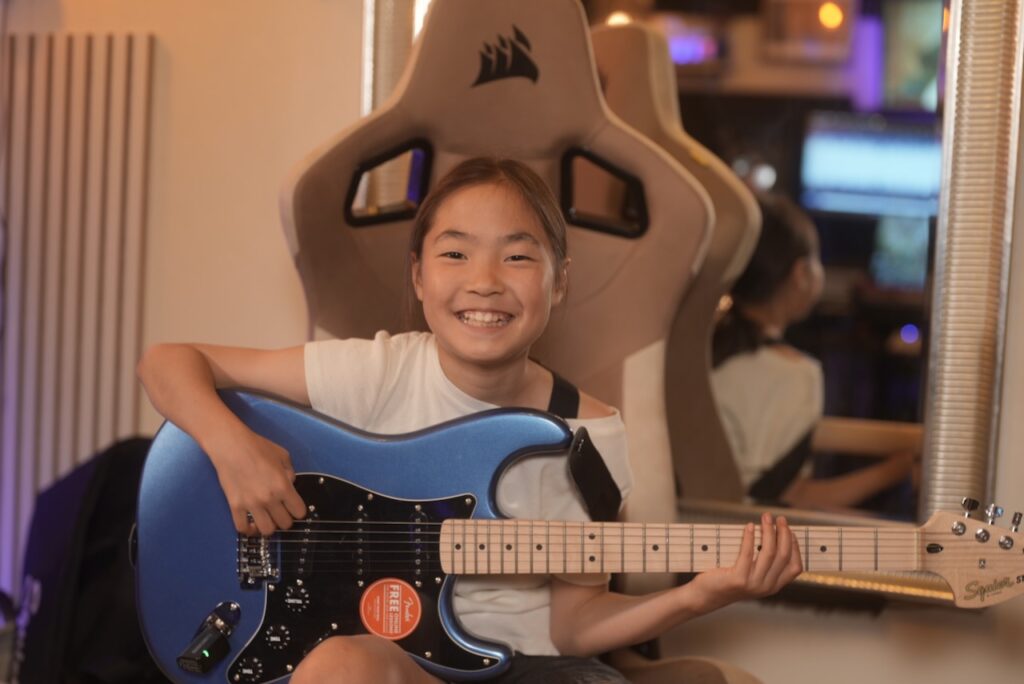 レッスンでギターを弾く女の子、小学生の生徒