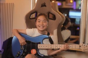 レッスンでギターを弾く女の子、小学生の生徒