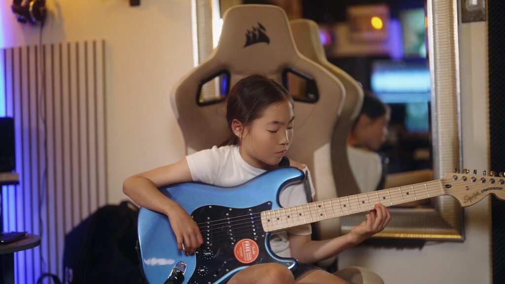 レッスンでギターを弾く女の子、小学生の生徒