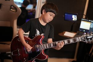 レッスンでギターを弾く小学2年生の生徒